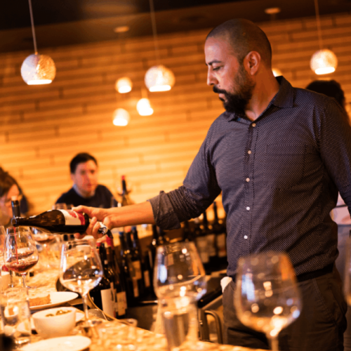 Flight Owner + Sommelier Kabir Amir pours wine at the bar.